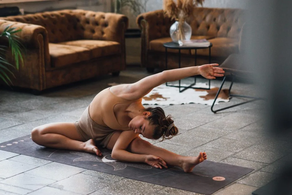 Jeune femme s'étirant dans une posture de yoga pour dormir, favorisant la relaxation avant le coucher