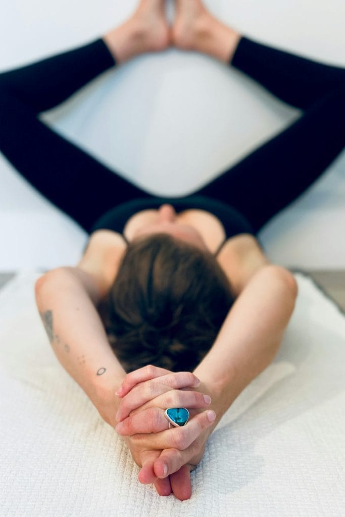 Jeune femme pratiquant la posture du papillon contre un mur pour développer sa souplesse grâce au yoga