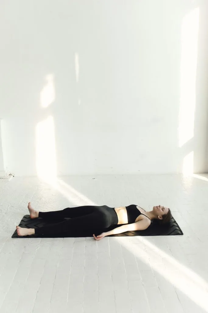 Jeune femme allongée sur le dos sur son tapis, en pleine séance de yoga nidra