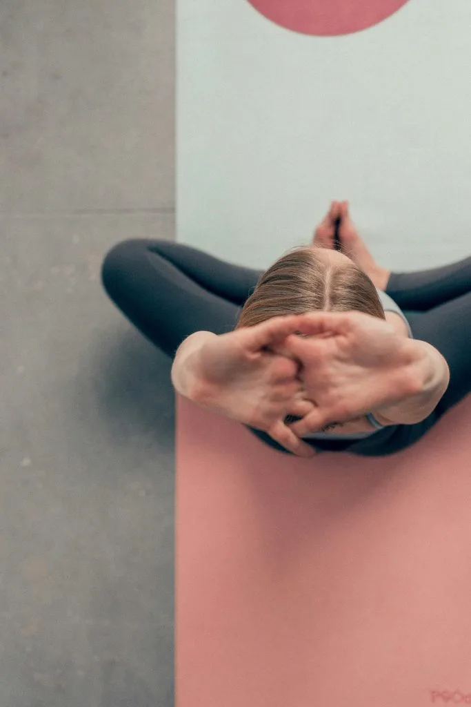 Jeune femme assise sur son tapis de yoga, s'étirant pour se détendre avec une pratique de yoga pour dormir