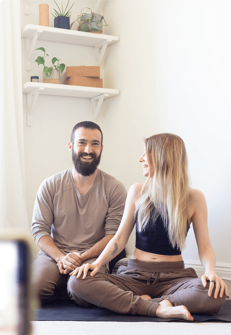 Deux professeurs de yoga assis sur un tapis, prêts à donner un cours de yoga en direct sur Zoom