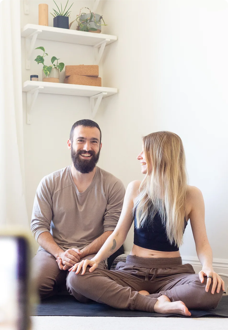 Deux professeurs de yoga assis sur un tapis, prêts à donner un cours de yoga en direct sur Zoom