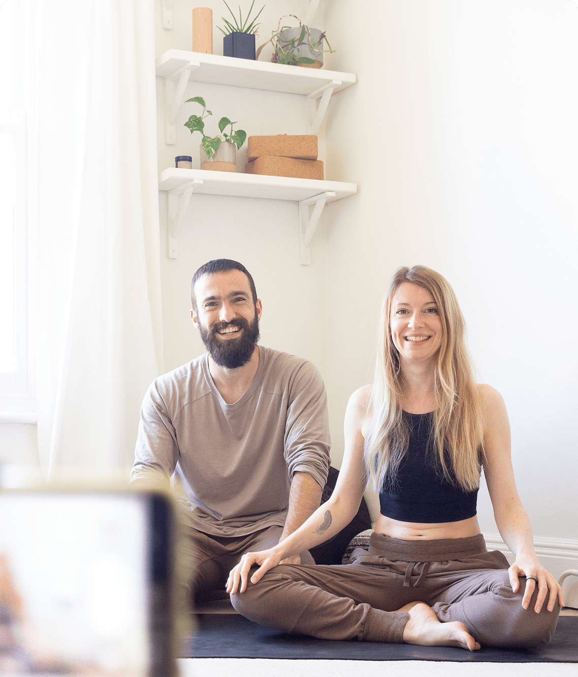 Deux professeurs de yoga assis sur un tapis, prêts à donner un cours de yoga en ligne sur Zoom